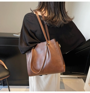 Detailed view of brown leather tote bag texture and high-quality metal buckle hardware