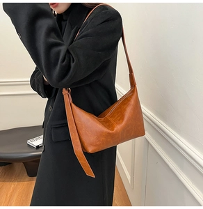 Close-up of caramel brown retro shoulder bag with glossy vintage leather texture