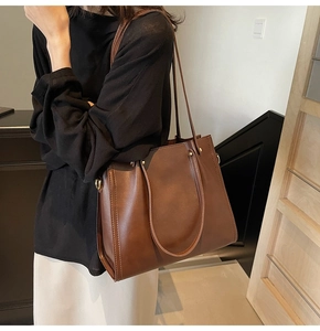 Detail of brown leather tote bag with fine stitching and gold metal hardware accents