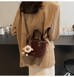 Detail of a brown leopard print crossbody bag with a cute white plush lamb pendant