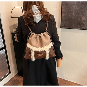 Detail of a brown leather backpack with cream faux fur trim and gold butterfly plate