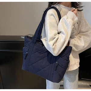Detail of navy blue quilted tote bag featuring classic diamond stitching and front zipper
