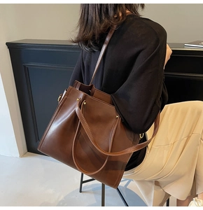 Close-up of a large dark brown PU leather tote bag with shoulder straps and metal details