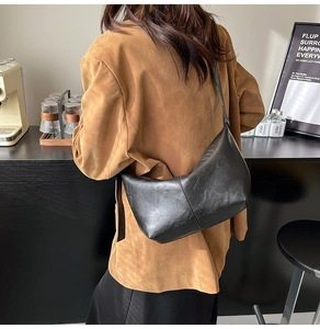 Detail of vintage matte black hobo bag with vertical stitching shown on model