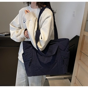 Detailed view of dark blue quilted tote bag with diamond pattern and side zip pockets