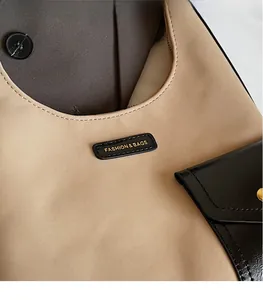 Close-up of golden logo plaque and contrast stitching on the beige stylish tote bag
