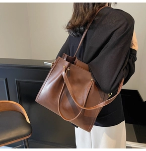 Detail of caramel brown tote bag showing wide shoulder straps and golden metal rings