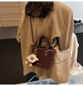 Detail of leopard print bucket bag with sheep charm and adjustable strap on a model