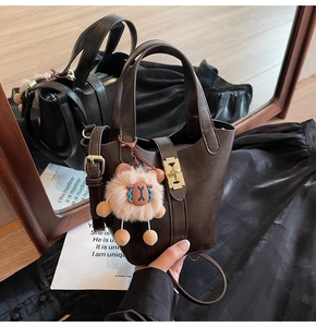 Detail of dark brown leather bucket bag with gold square twist lock and cute lion charm