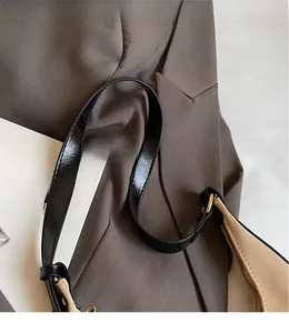 Detail of adjustable black leather strap and metal buckle on beige tote shoulder bag
