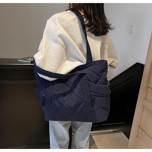 Detail view of quilted blue tote bag showing side zipper and rhombus pattern