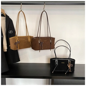 Close-up of matte suede tote bags with slim shoulder straps and woven bow pendants