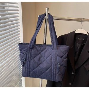 Close-up of quilted pattern and side zipper pocket on dark blue tote bag