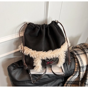 Detail of black drawstring backpack with white faux fur trim and bow metal plaque
