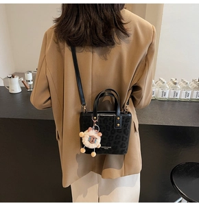Detail of black leopard print bucket bag with a cute plush sheep charm and crossbody strap