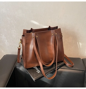 Detail of a brown leather tote bag showing smooth texture and adjustable shoulder strap