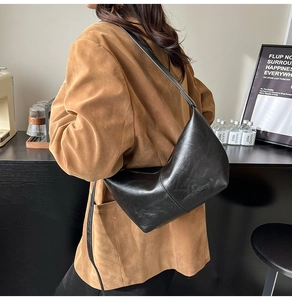 Detail of black crescent shoulder bag featuring fine pleated texture and matte finish