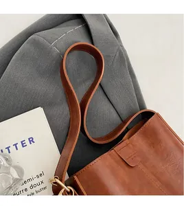 Close-up of brown leather bucket bag with golden metal ring and smooth long shoulder strap