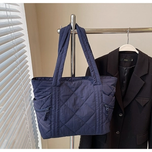 Detail of navy blue quilted puffer tote bag with side zipper and nylon texture