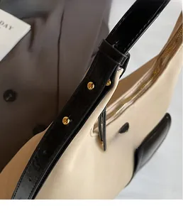 Detail of a beige leather tote with golden rivets and black straps on a blazer