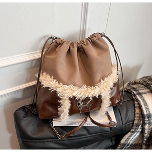 Detail of drawstring bucket bag with brown leather, beige faux fur, and silver butterfly charm