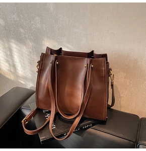 Detail of dark brown tote bag with adjustable strap and shiny gold-tone hardware