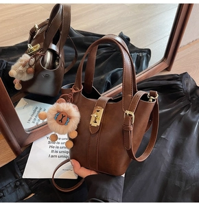 Detailed view of brown PU leather bucket bag with gold hardware and plush lion charm