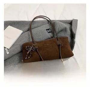 Detail of dark brown matte tote bag featuring braided knot charm and slim double handles