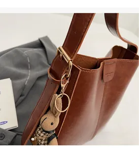 Detail of vintage brown leather bag with golden buckle and cute rabbit doll charm