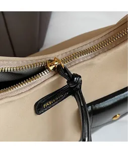 Detail of smooth gold metal zipper and leather puller on a beige hobo shoulder bag