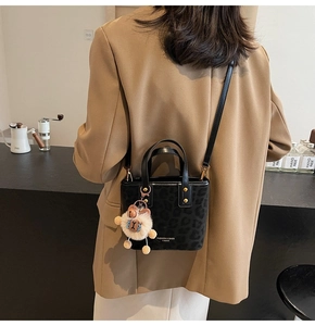 Detailed back view of a black leopard print mini bucket bag with a plush sheep charm