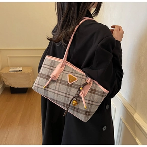 Détails des finitions en cuir rose et pendentif tissé brun sur le sac cabas à carreaux