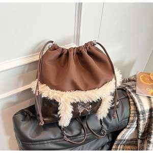 Detail of dark brown bucket bag with white faux fur trim and silver butterfly pendant