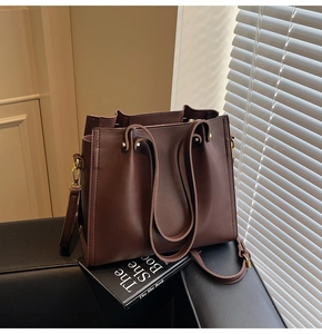 Detail of dark brown leather tote bag showing gold hardware and smooth texture