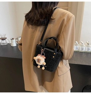 Detail of black leopard print bucket bag with gold hardware and plush sheep charm decoration