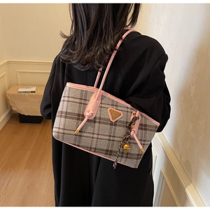 Détail du cabas à carreaux gris avec bordure en cuir rose et breloque sur le mannequin