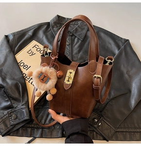 Detailed close-up of brown leather bucket bag with gold lock and plush lion charm