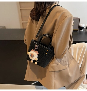 Detail of leopard print bucket bag with detachable strap and plush sheep charm on a model