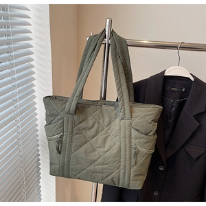Close-up of quilted olive tote bag with side zipper pockets and wide shoulder straps