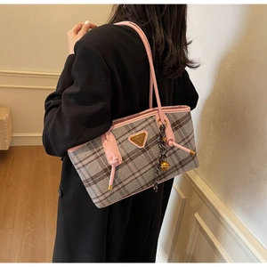 Détail de la bandoulière en cuir rose et du tissu en laine à carreaux du sac à main