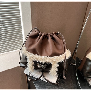 Detail view of a vintage brown bucket bag with plush trim and a silver butterfly buckle
