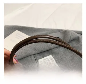 Detail of soft brown leather handle with precision stitching on a large tote bag