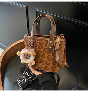 Detail of leopard print bucket bag featuring a white plush sheep charm and gold metal hardware