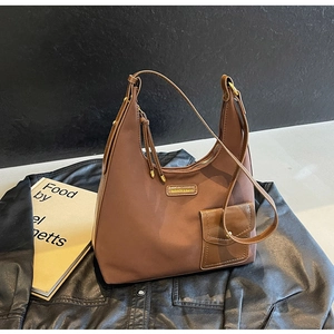Close-up of brown crescent hobo bag with gold logo on black leather jacket background