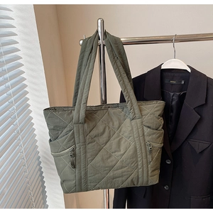 Close-up of olive green quilted nylon tote bag featuring vertical side zipper pockets