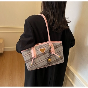 Détail de la bandoulière rose et laine grise à carreaux sur le sac porté