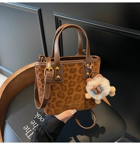 Detail of leopard print bucket bag with dual handles and plush bear charm