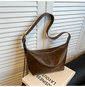 Detail of vintage dark brown faux leather dumpling bag with adjustable strap on art book