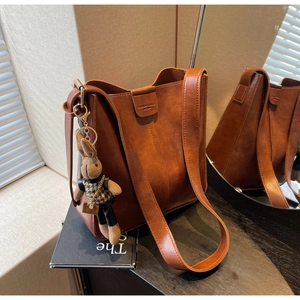 Detailed shot of brown vintage bucket bag with a cute rabbit doll and magnetic closure
