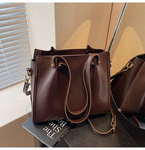 Detail of dark brown leather tote bag with gold hardware and multi-compartment design